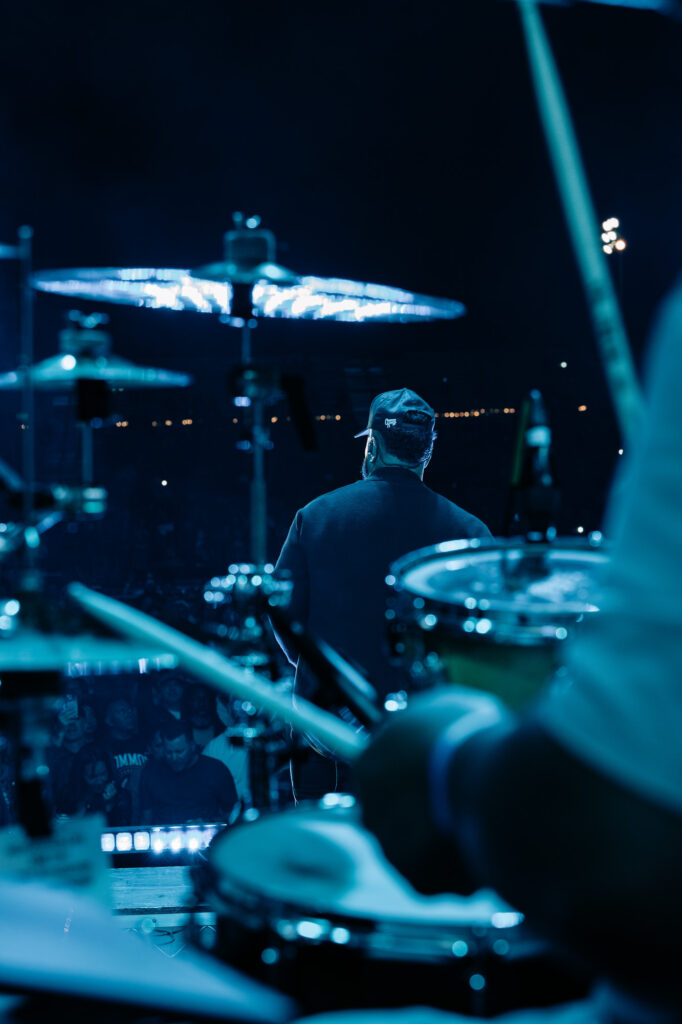 Common-Kings-Concert-Los-Angeles-May-23-2026-by-Zharmaaaine-111 – The 824 Journal Drummer seen from behind on a blue-lit concert stage, surrounded by cymbals and drums at night.