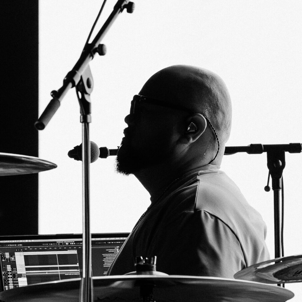 Common-Kings-Concert-Los-Angeles-May-23-2026-by-Zharmaaaine-119 – The 824 Journal Black-and-white photo of a drummer wearing headphones, seated at a drum kit with a microphone in front and cymbals visible.