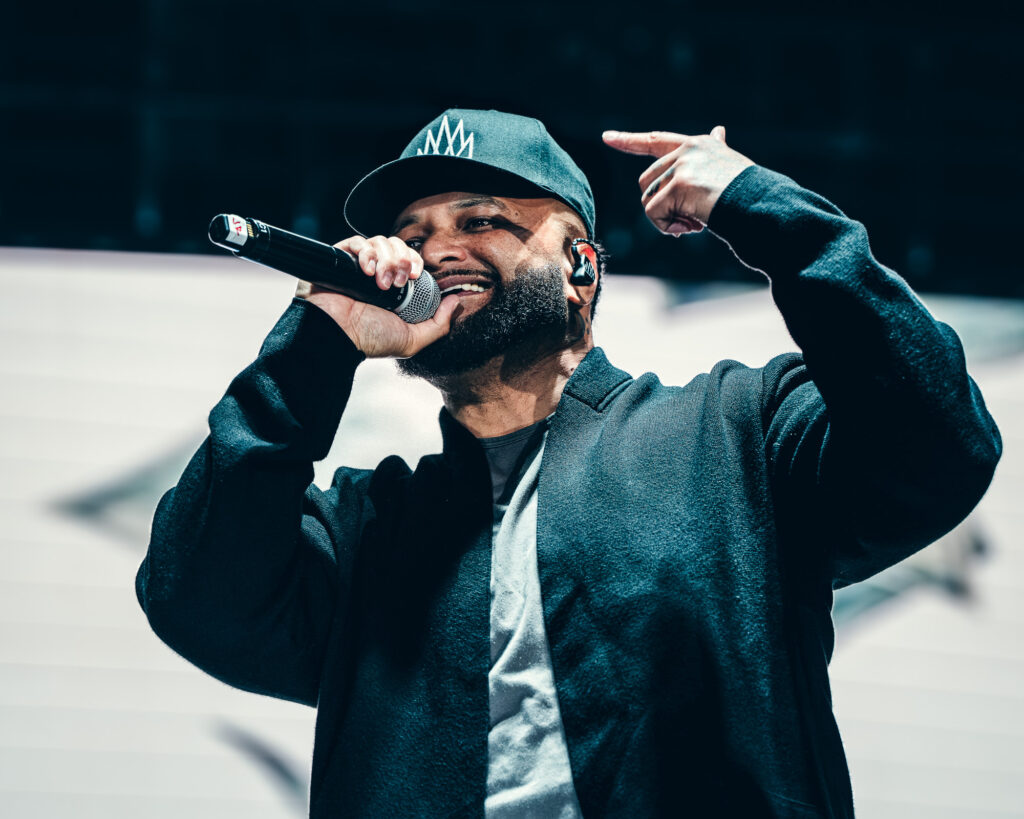 Common-Kings-Concert-Los-Angeles-May-23-2026-by-Zharmaaaine-49 – The 824 Journal Singer on stage holding a microphone, wearing a cap and dark hoodie, mid-performance with expressive gesture