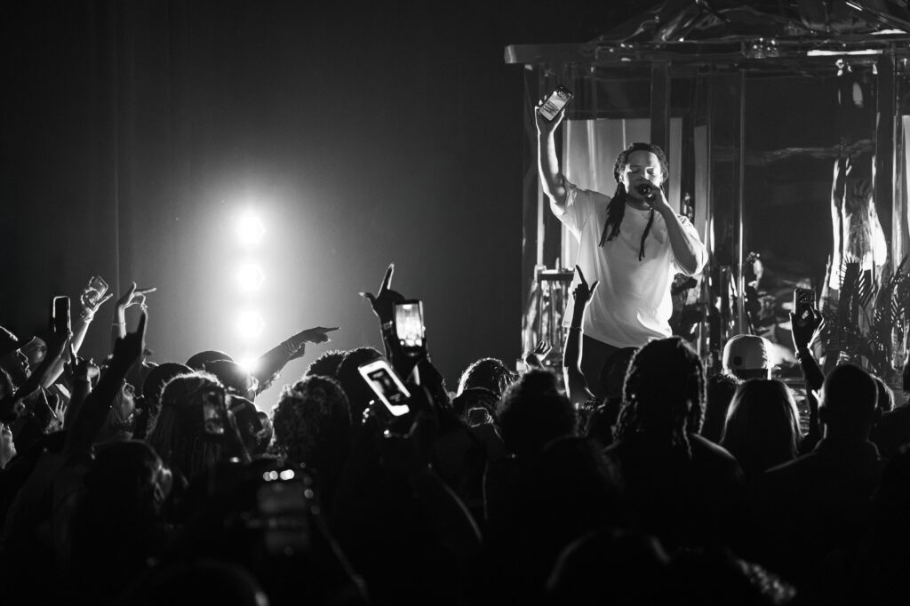 Domani-The-Echo-Los-Angeles-June-23-2026-by-Zharmaine-Boatman-IG-zharmaaaine-38-2 – The 824 Journal Black-and-white concert scene: performer on stage raises a smartphone toward the crowd while singing, fans hold up phones in the foreground.