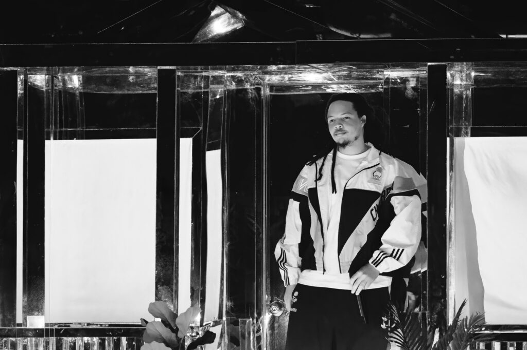 Domani-The-Echo-Los-Angeles-June-23-2026-by-Zharmaine-Boatman-IG-zharmaaaine-7 – The 824 Journal Man in a color-block jacket stands inside a glass-walled doorway, looking toward the camera.