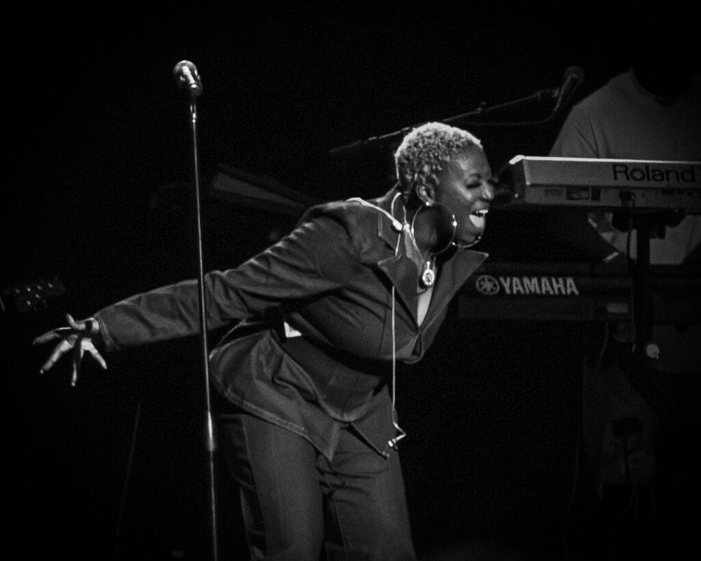 Musiq-Soulchild-The-Grove-of-Anaheim-May-29-2026-22 – The 824 Journal Black-and-white photo of a female singer leaning forward, microphone nearby, with a Yamaha keyboard in the background on stage.
