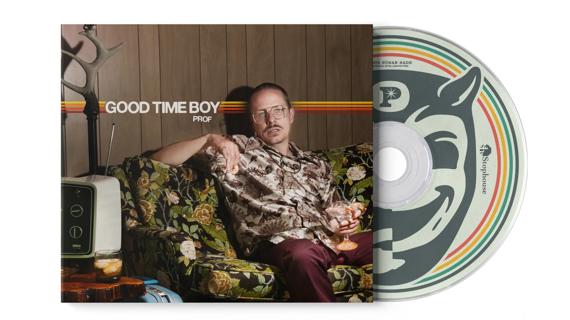 PROF_GTB_CD_WOODGRAIN_1024x1024@2x.jpg – The 824 Journal Man relaxing on a floral sofa in a retro room, holding a drink, with a large vinyl record edge showing on the right.