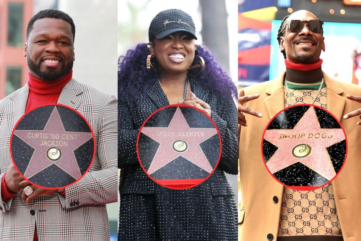 Three smiling adults pose with pink star plaques encircled in red, standing on a city street; left wears a gray plaid suit, middle in black dotted outfit, right in tan coat and sunglasses.