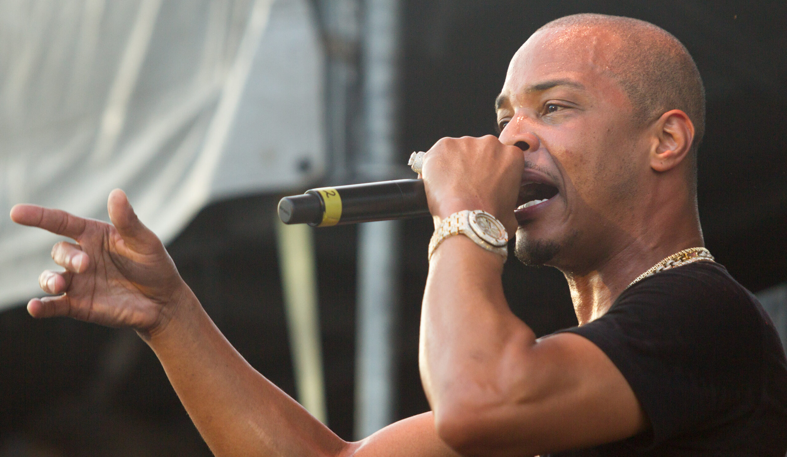 T.I. performing on stage, pointing toward the crowd with a microphone in hand.