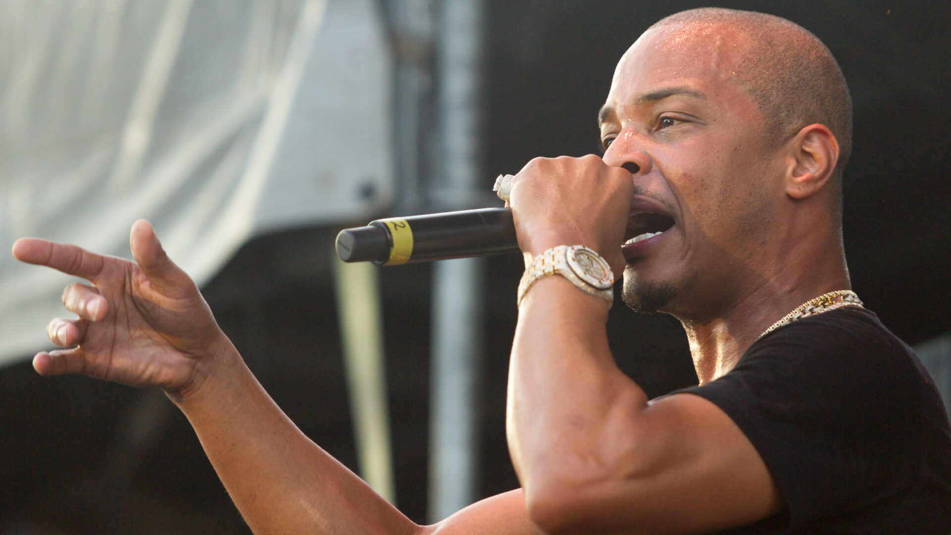 Rapper,T.i.,On,Stage,At,One,Music,Festival,2018, – The 824 Journal Male singer on stage, singing into a microphone with his left hand extended toward the audience.