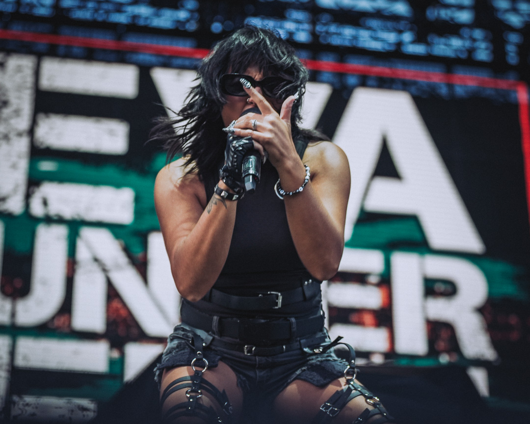 Eva Under Fire at F&M Bank Amphitheater in Long Beach: female rock singer on stage, wearing a black sleeveless outfit and sunglasses.