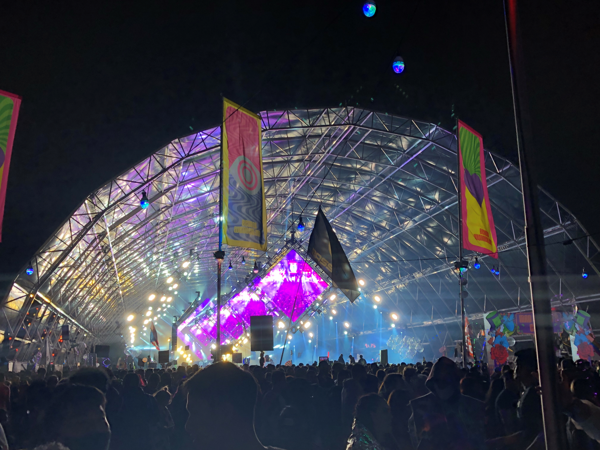 The Mad Hatter's Castle stage at Beyond Wonderland lit in purple and blue under a large arched structure at night
