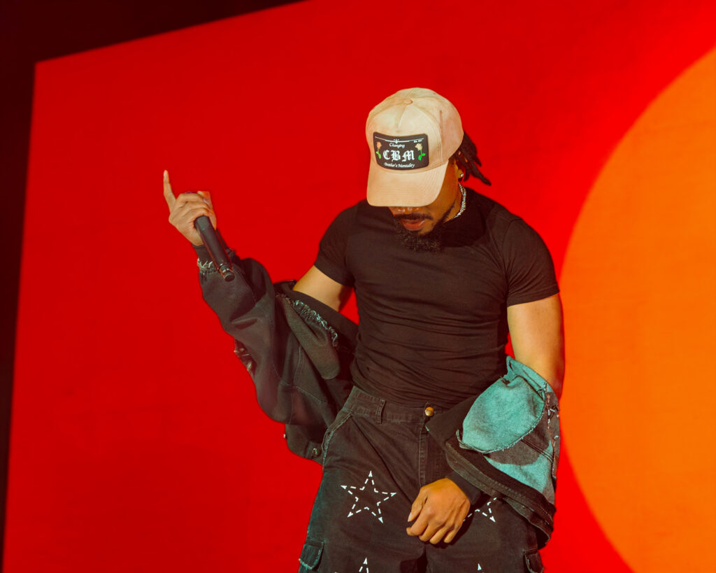 Chance the Rapper at Hollywood Palladium, Los Angeles, September 20, 2026 (28) – The 824 Journal Chance the Rapper performing at the Hollywood Palladium in a beige cap with a denim jacket tied at his waist, microphone raised against a red-orange backdrop.
