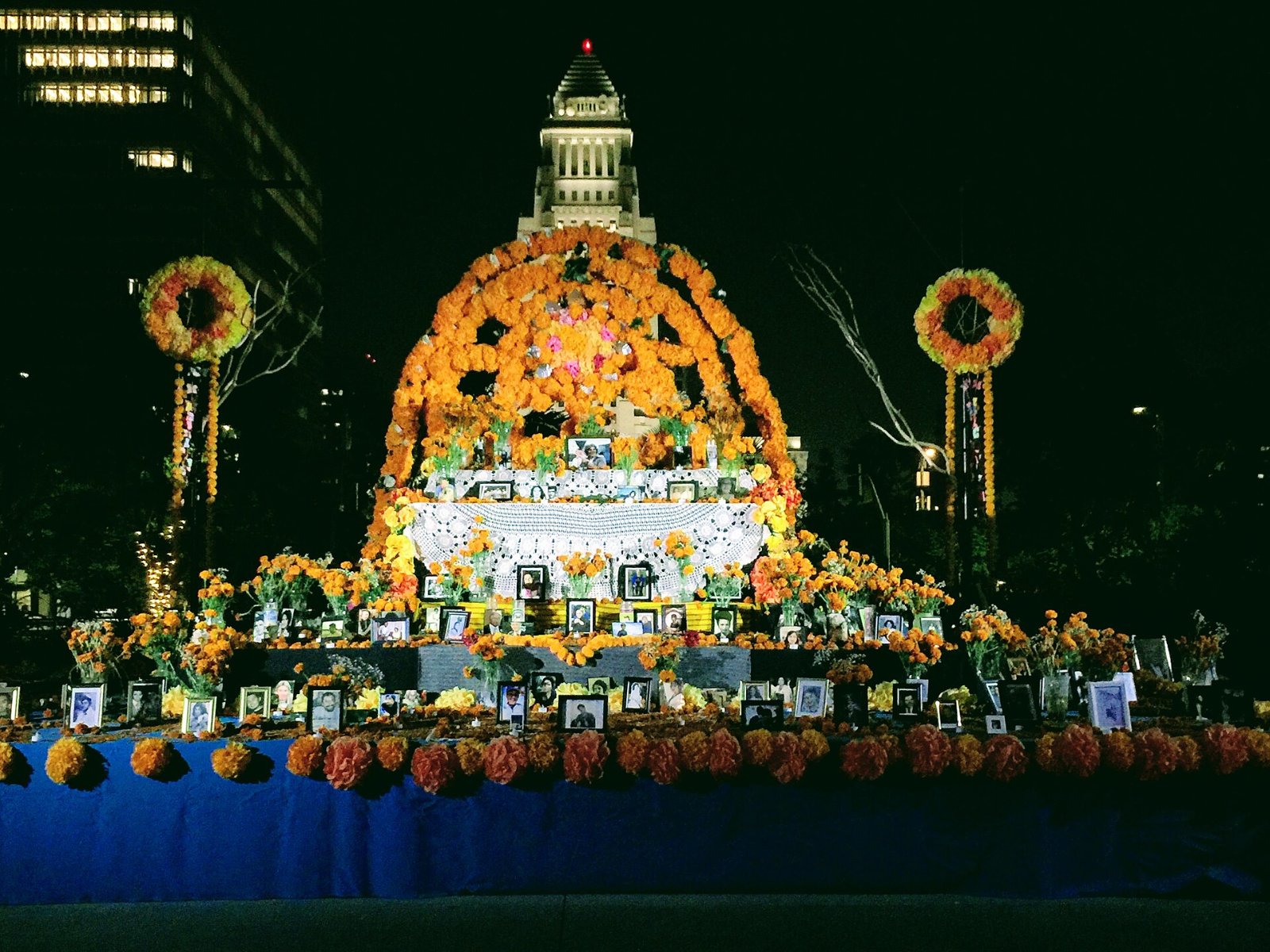 A Día de los Muertos altar decorated with marigolds at Grand Park in Los Angeles, with City Hall behind it