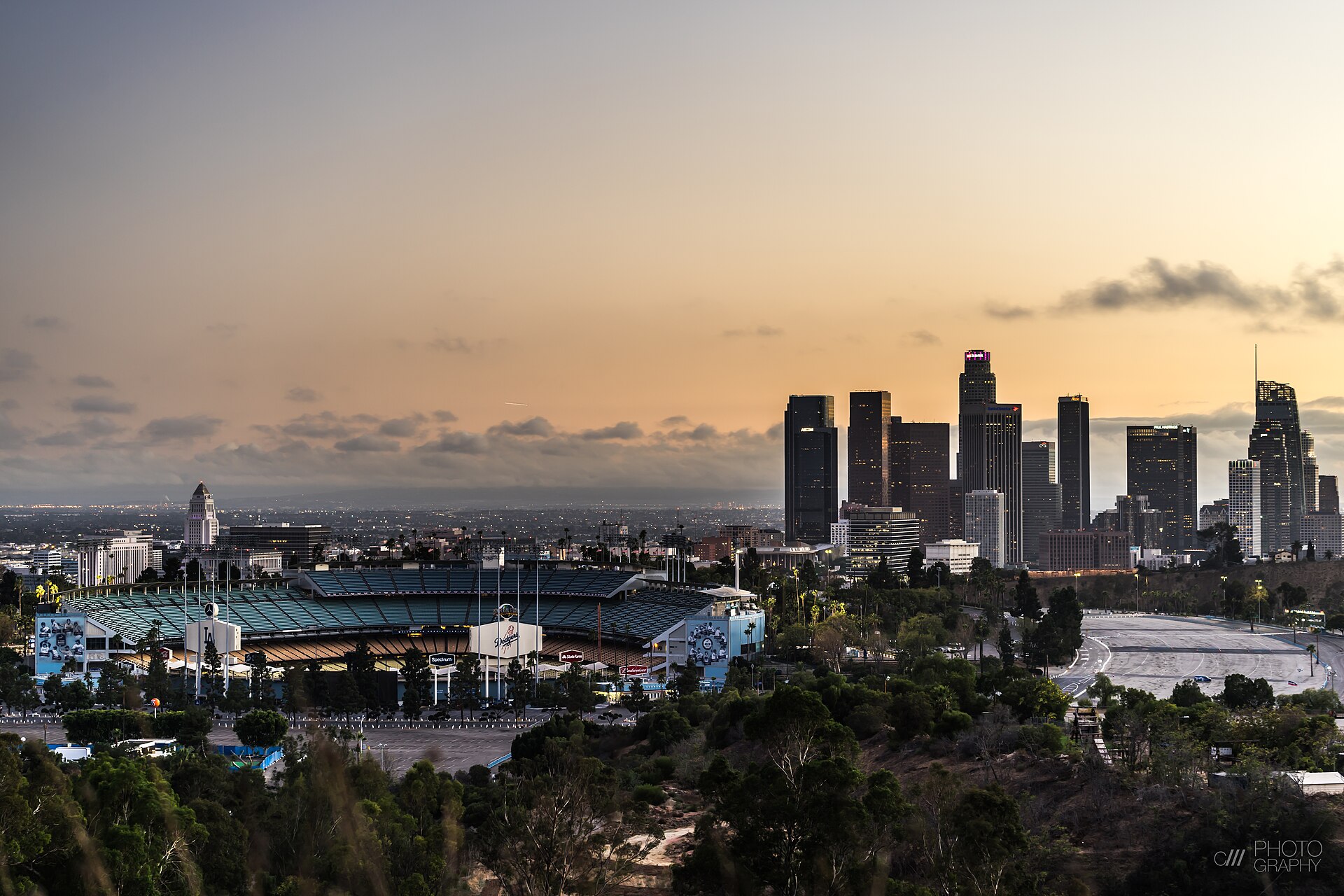 Dodger Stadium at golden hour with the downtown Los Angeles skyline rising behind it