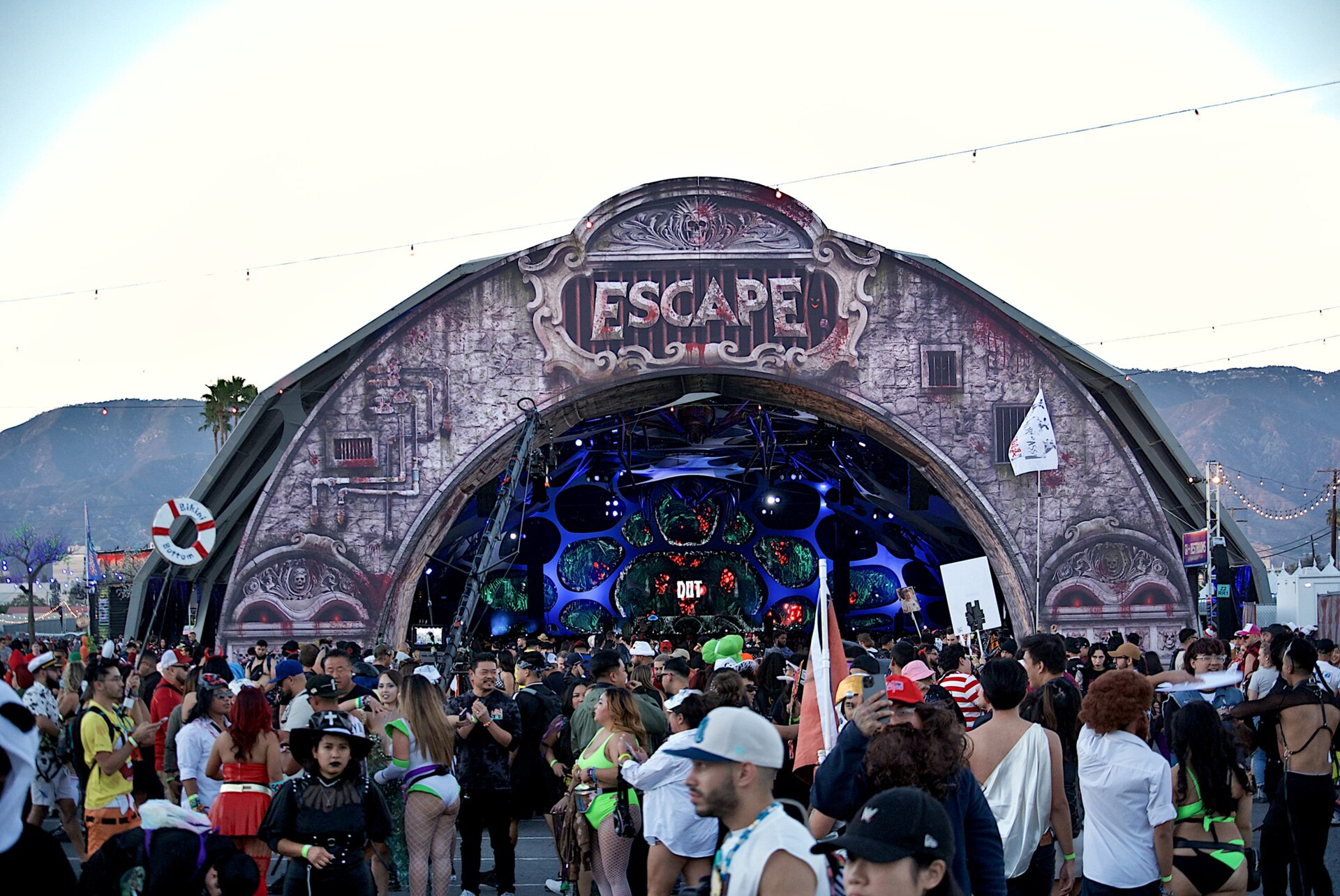 Crowds walking beneath the ornate Escape archway at dusk at the NOS Events Center in San Bernardino