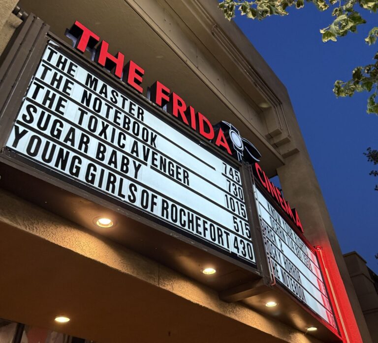 The lit marquee of The Frida Cinema in downtown Santa Ana listing film titles