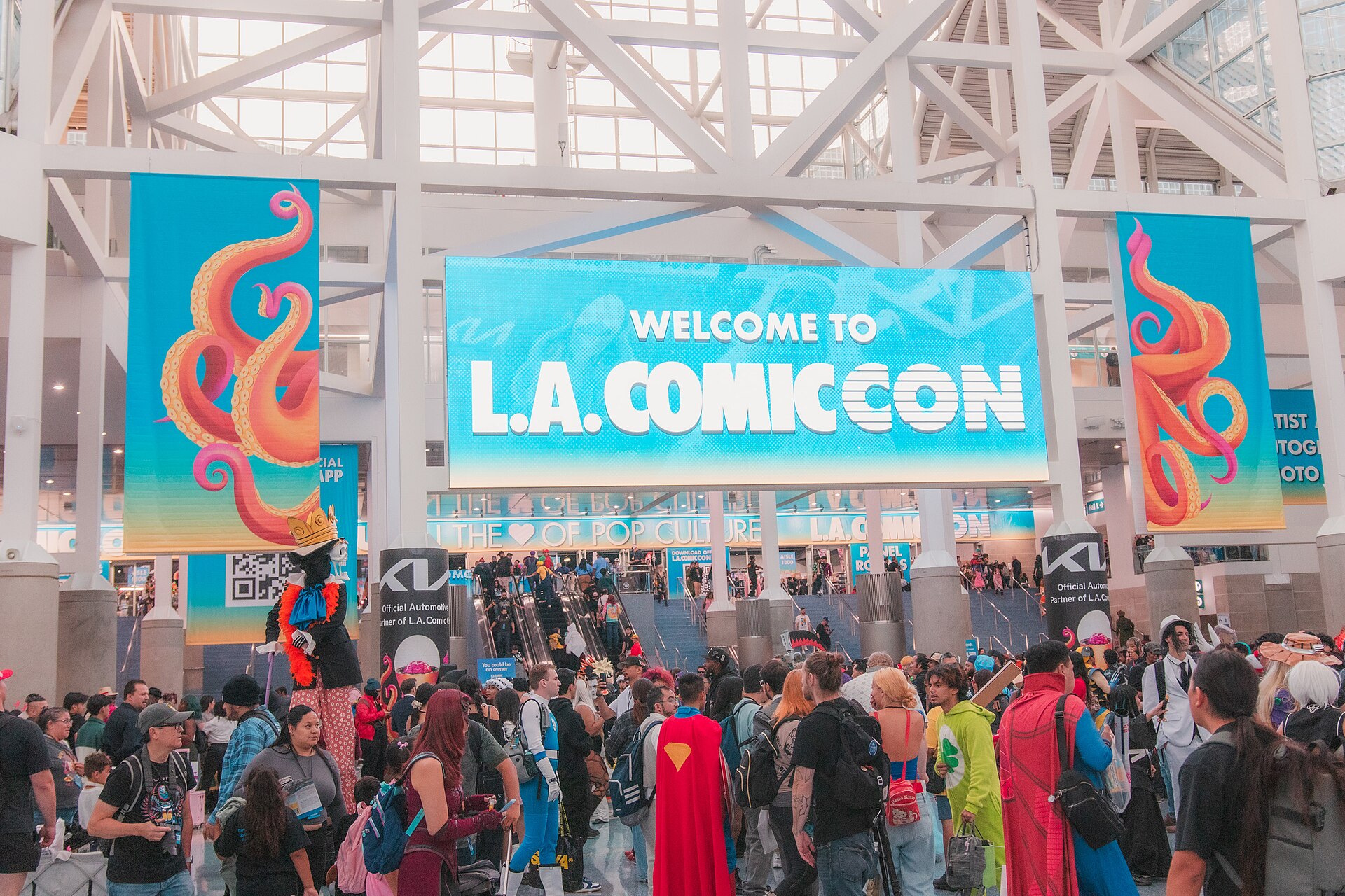 Crowds of fans, some in costume, gather under a large Welcome to L.A. Comic Con banner inside the Los Angeles Convention Center lobby