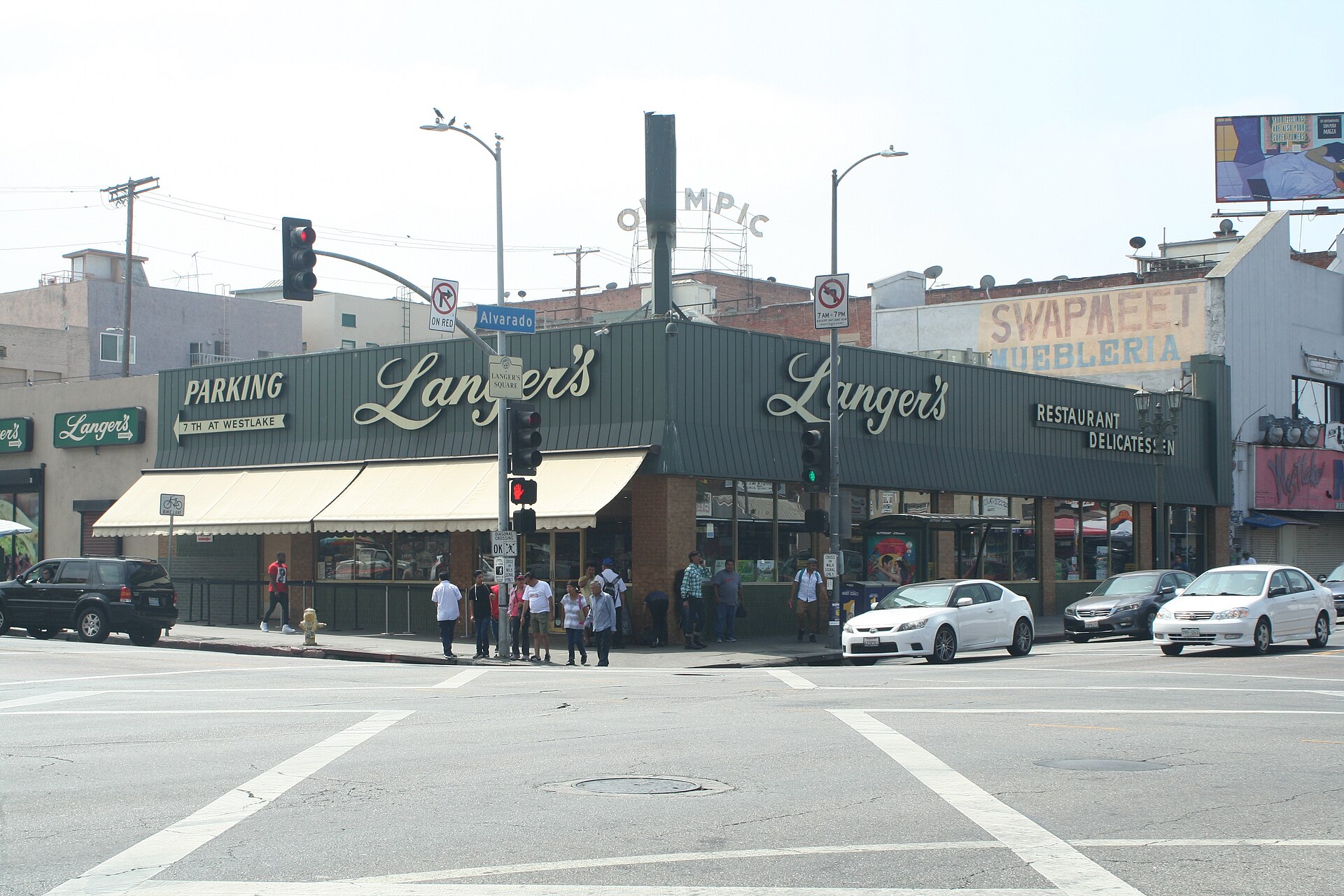 The green-trimmed exterior of Langer's Delicatessen on a street corner in Los Angeles, with its script signs above the awnings
