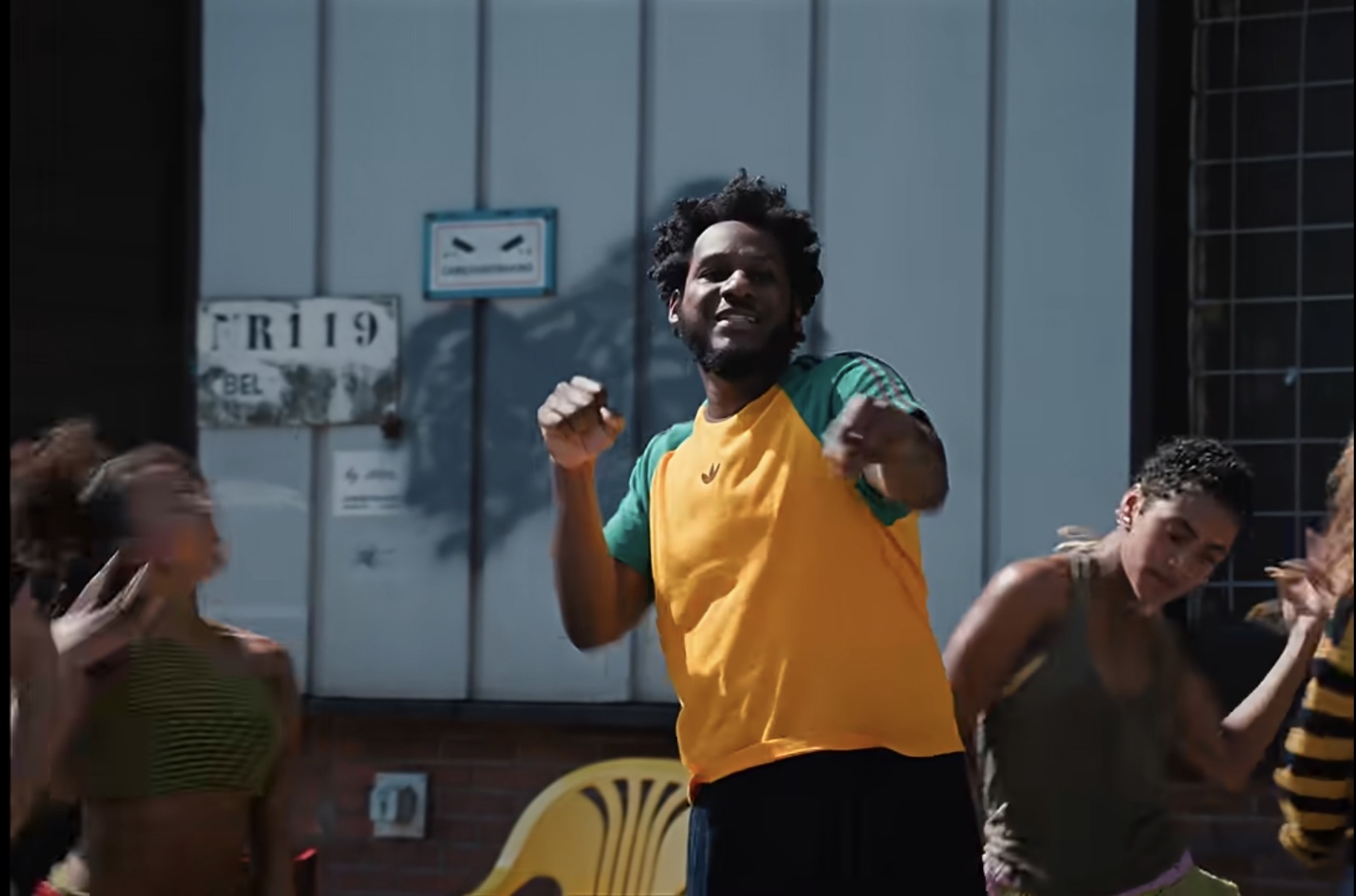 Still from a Leon Bridges music video showing a man dancing in a yellow and green shirt.