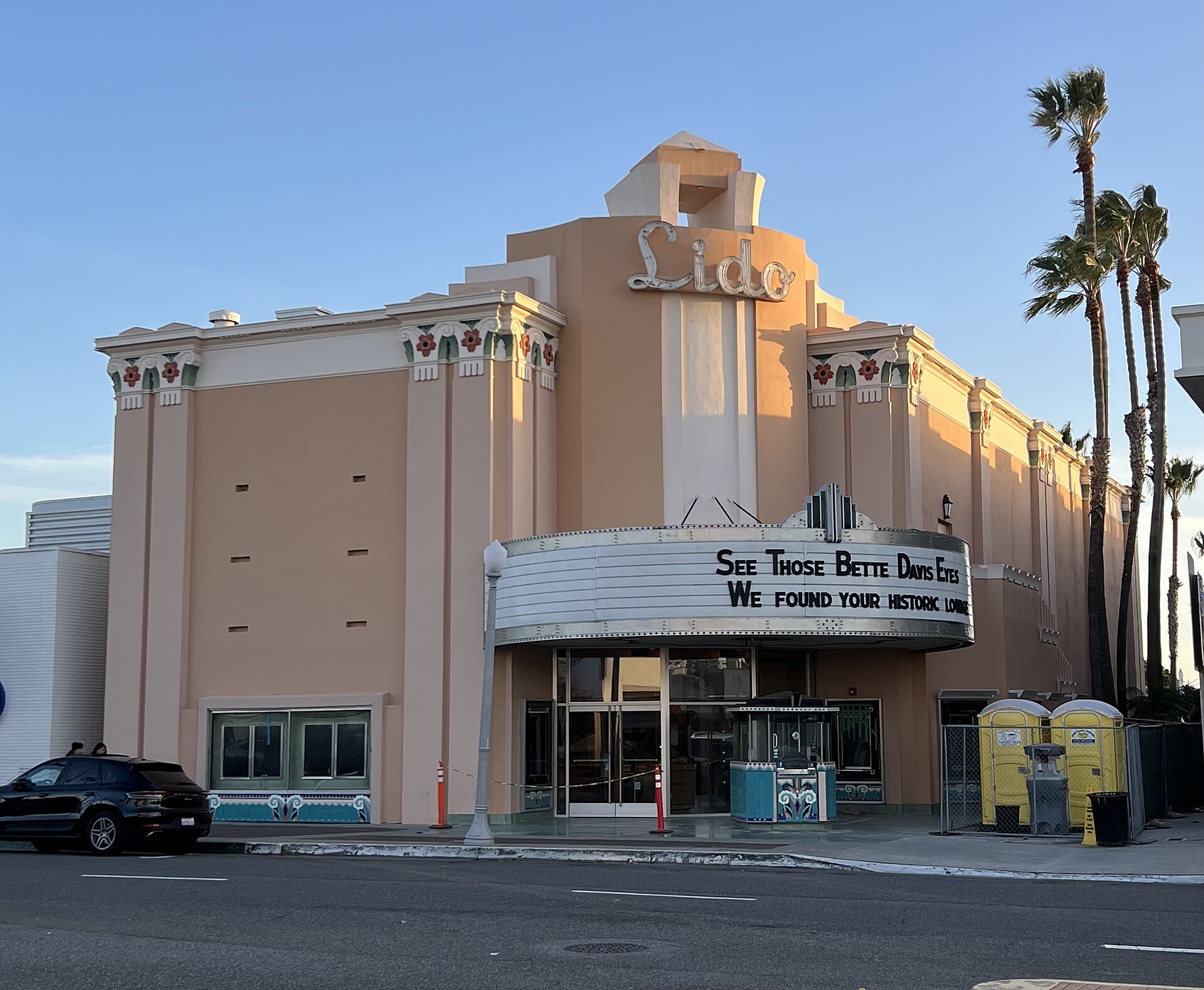 The Art Deco Lido Theater on Via Lido in Newport Beach, with its marquee and palm trees under a clear sky