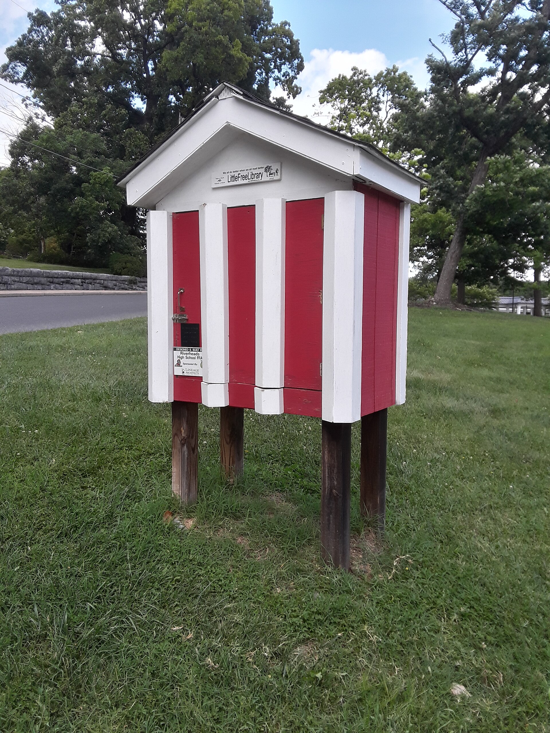 A wooden Little Free Library book box on a post, filled with books