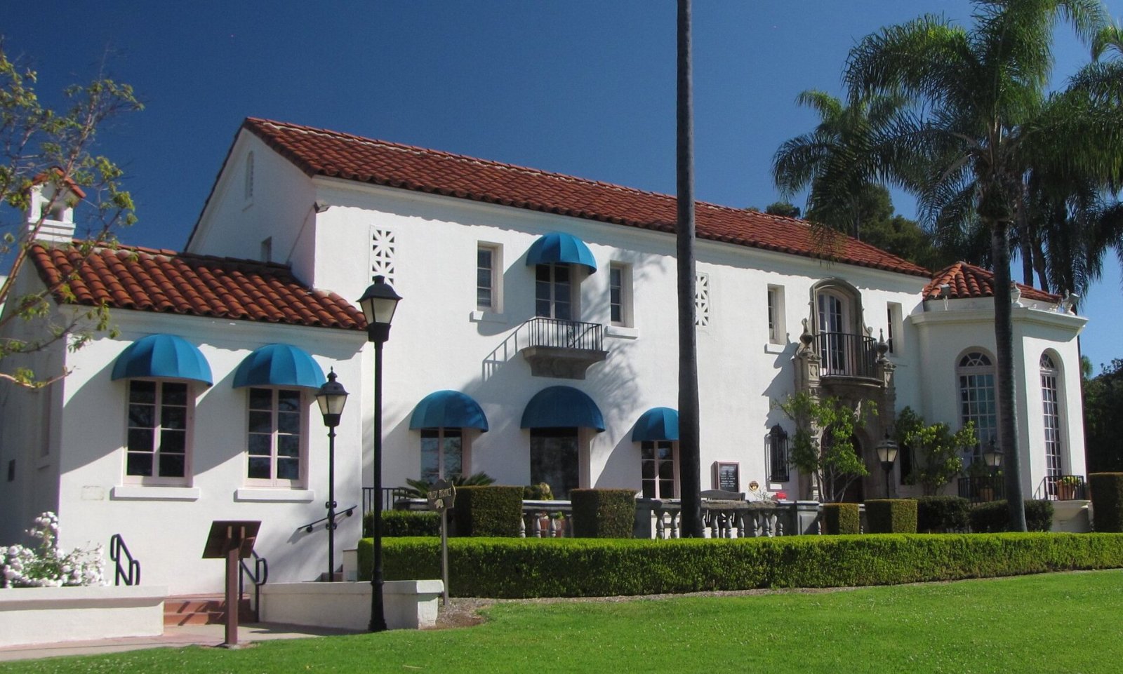 The white Spanish-style Muckenthaler mansion in Fullerton with blue awnings and a red tile roof