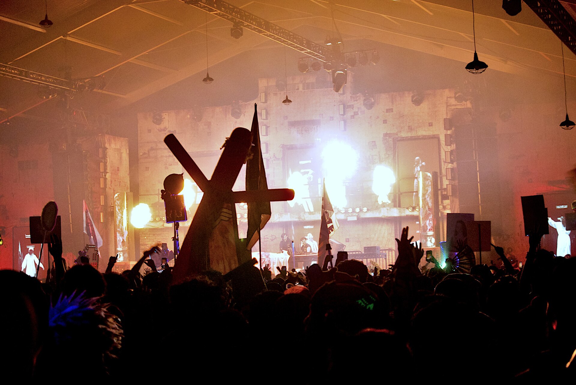 Pyrotechnic flames shooting up from an indoor stage over a crowd at the NOS Events Center