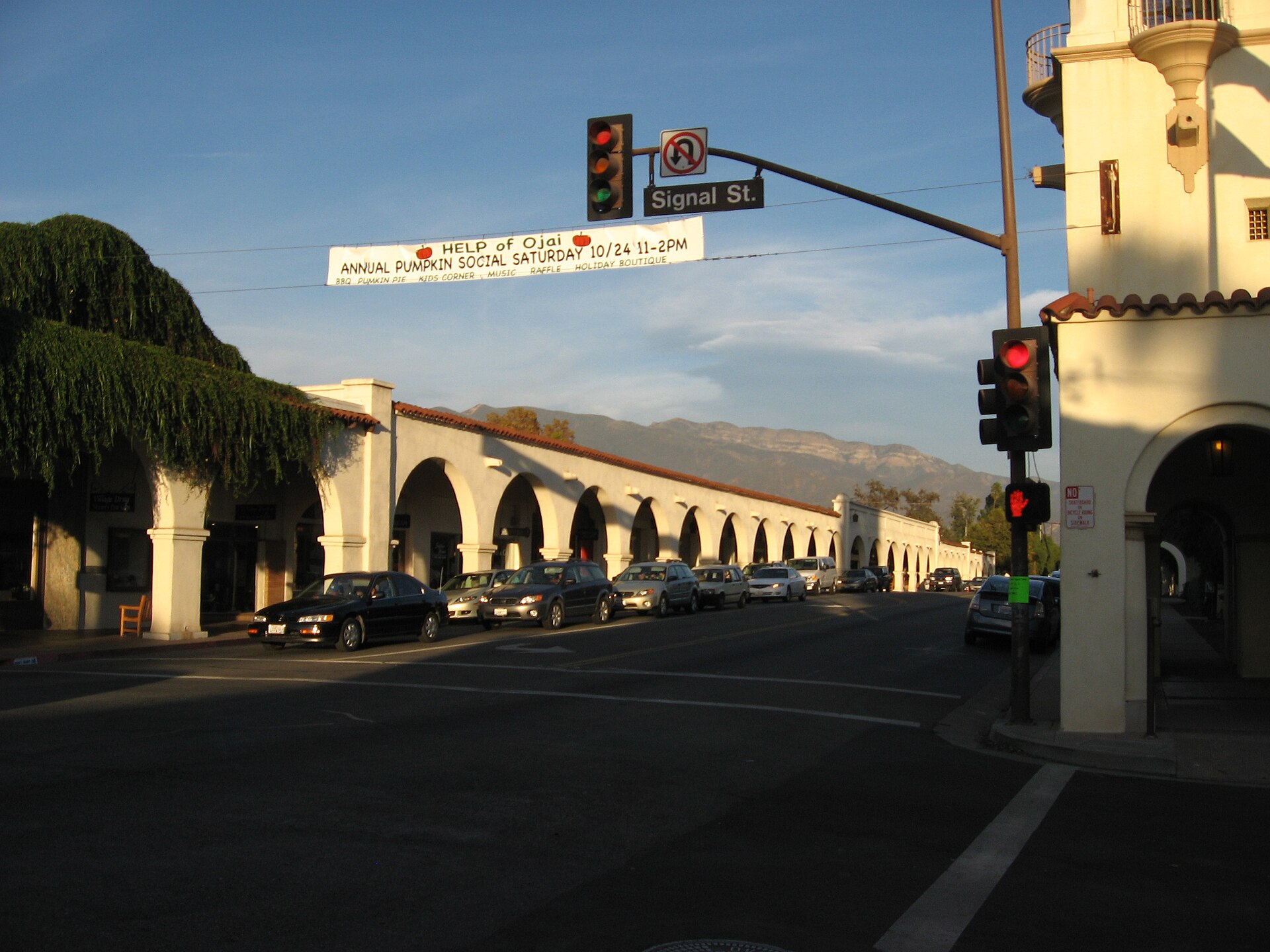 The white arched Spanish Colonial Revival arcade along Ojai's main street, with a traffic signal and a banner over the road