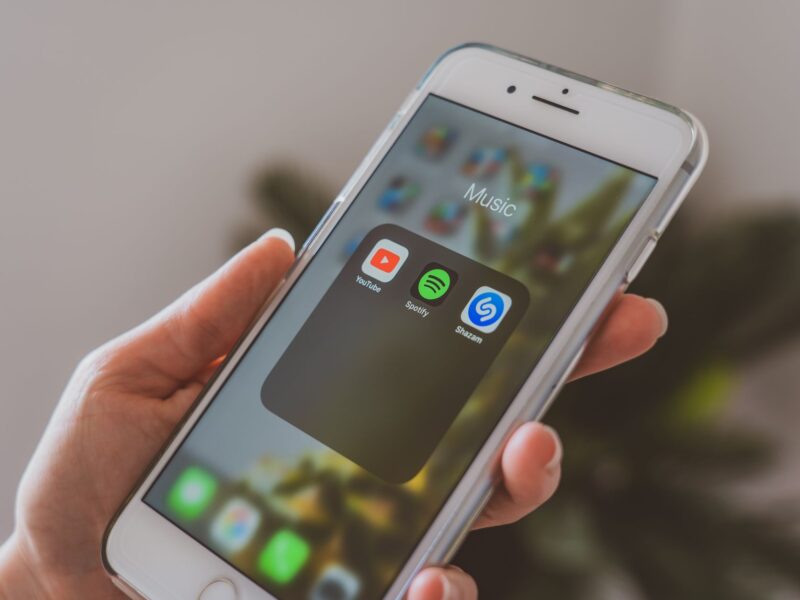 Hand holding an iPhone open to a folder of music apps.