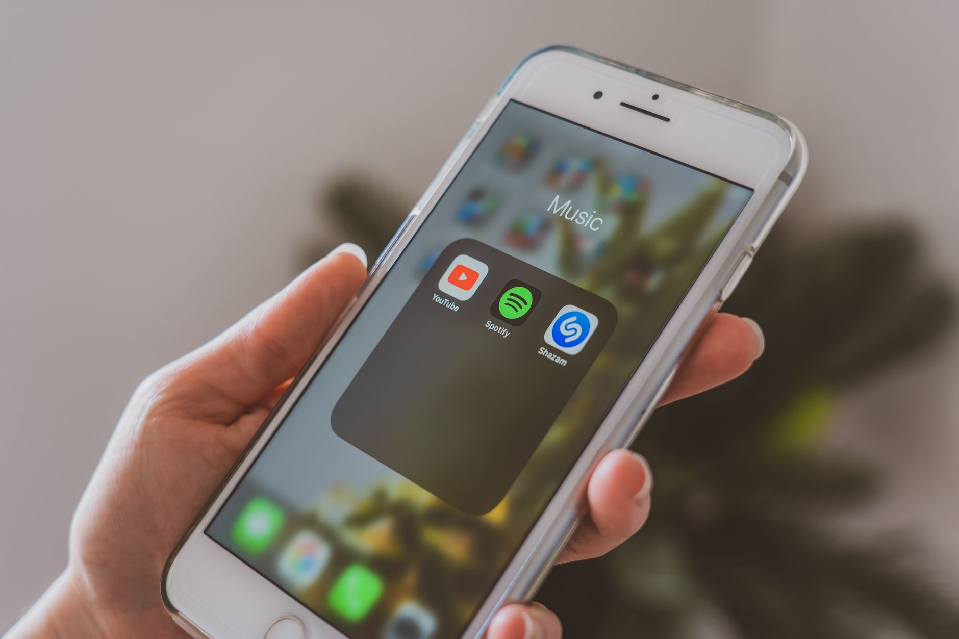 Hand holding an iPhone open to a folder of music apps.