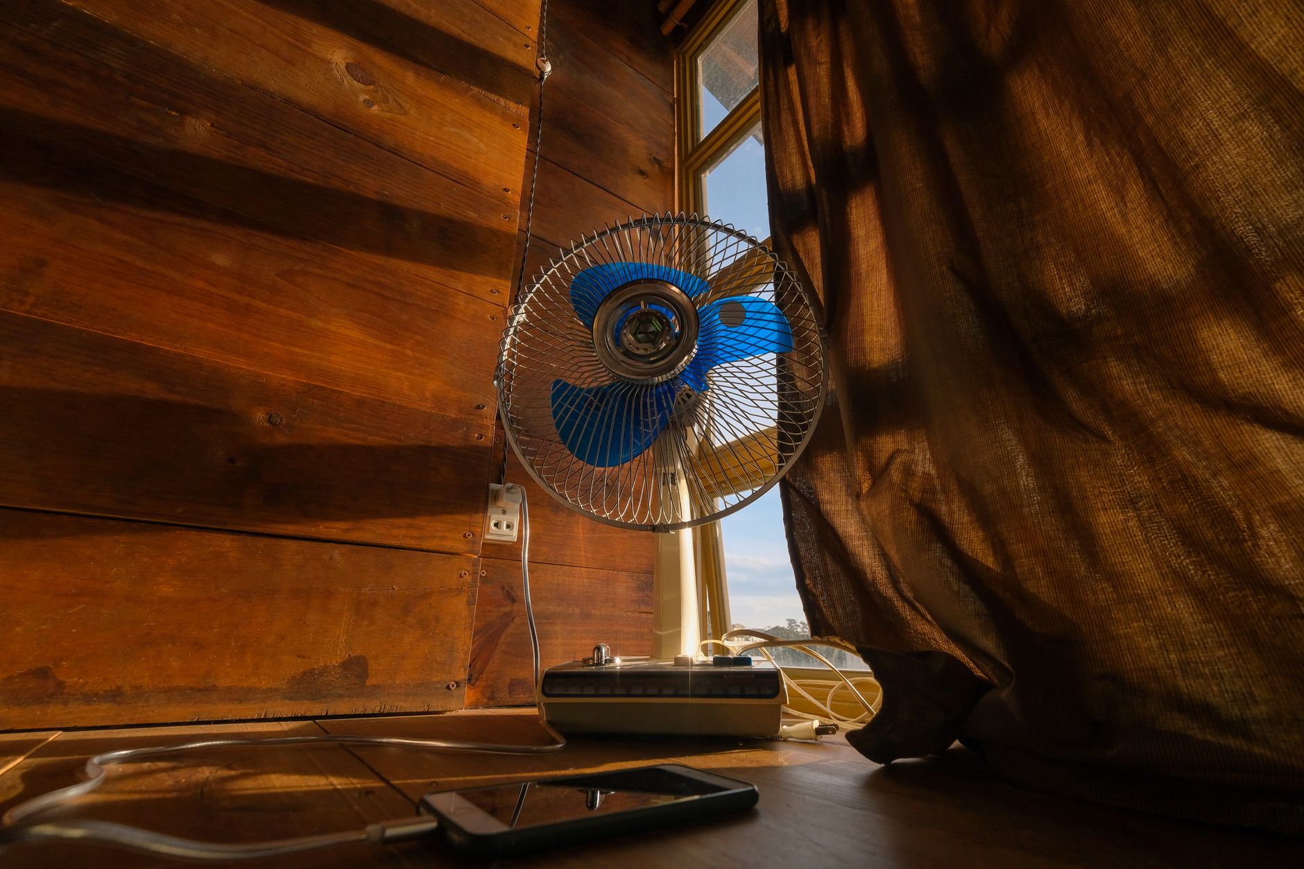 electric fan beside a window