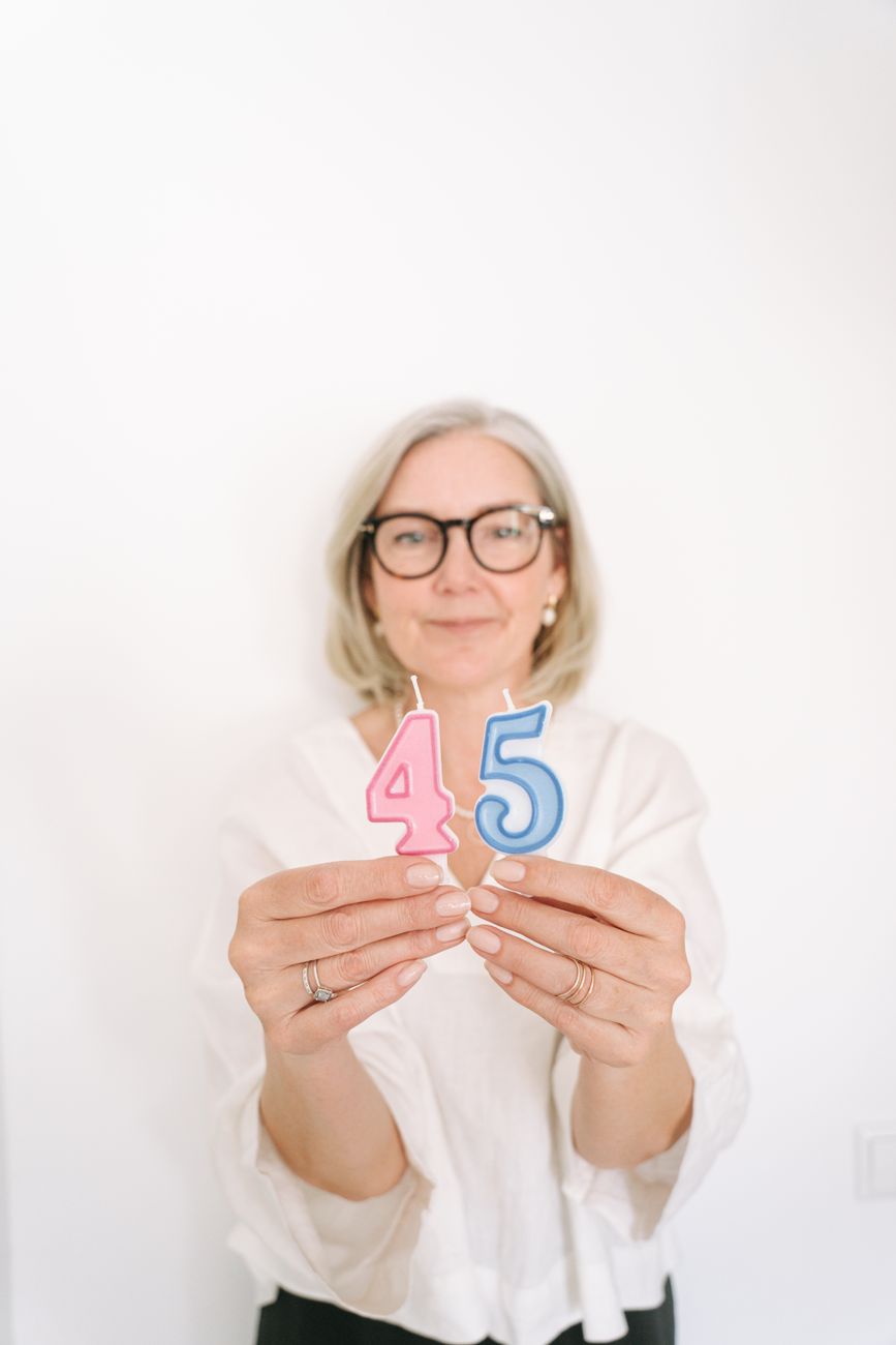 Smiling woman holding number 4 and 5 birthday candles.