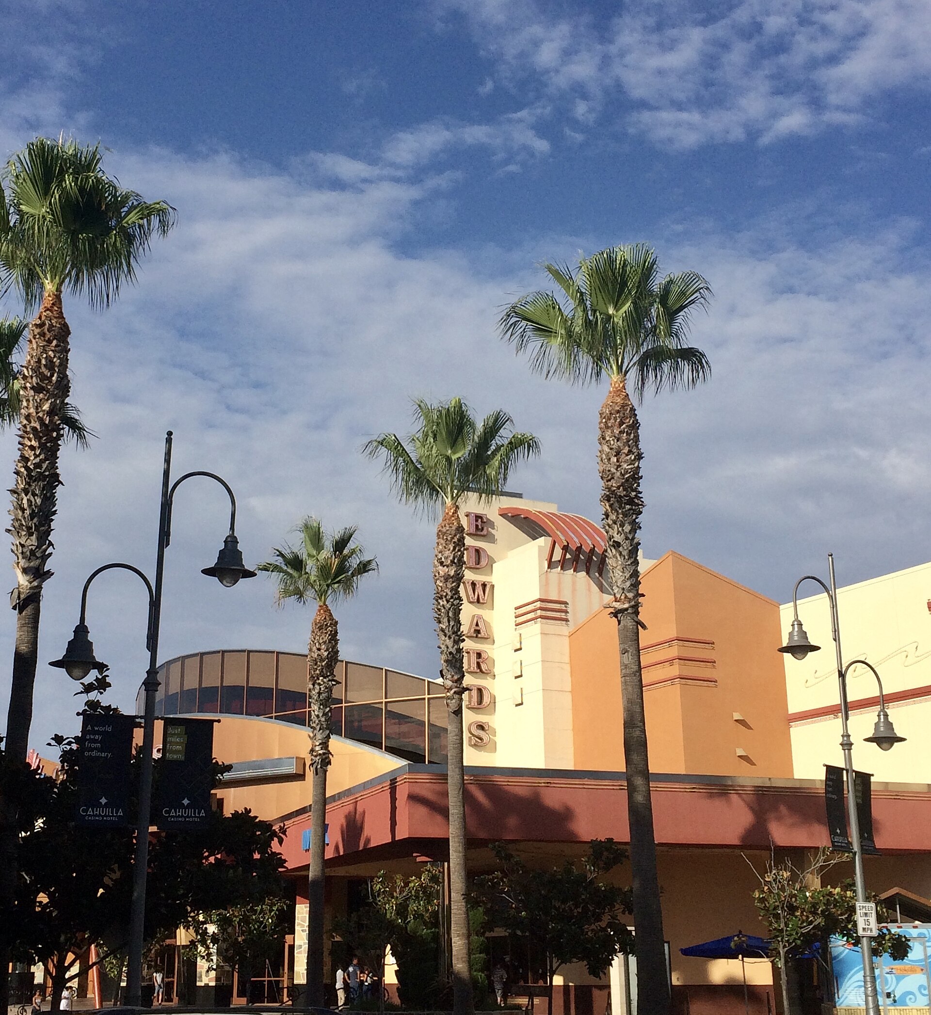 Palm trees in front of the Edwards Cinema building at the Promenade Temecula shopping mall under a blue sky