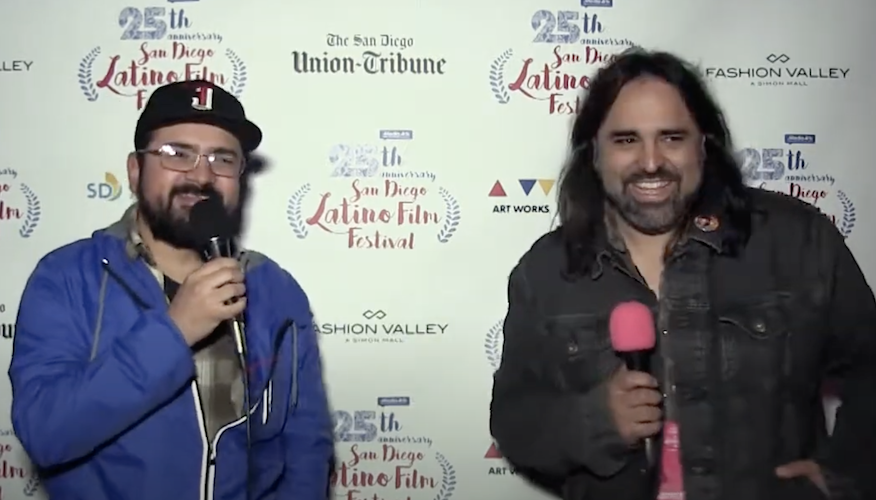 Two men holding microphones in front of a San Diego Latino Film Festival press backdrop