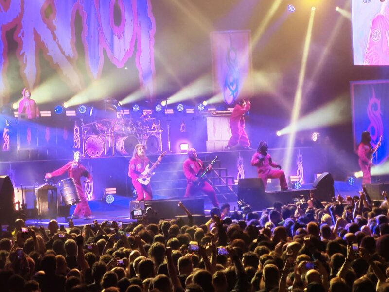 Slipknot performing on stage at the O2 Arena in London under purple and white stage lights, December 2024