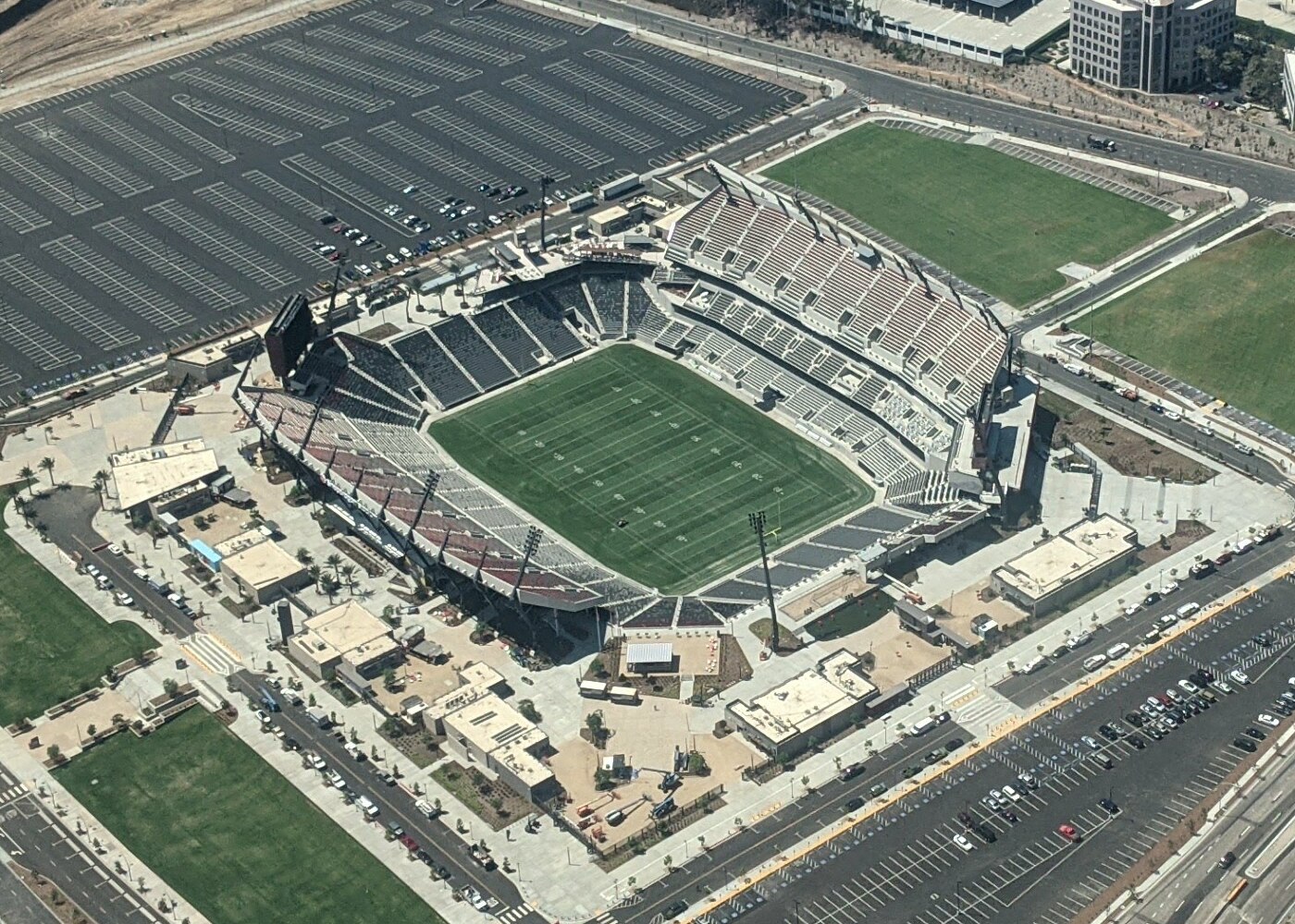 Aerial view of Snapdragon Stadium in San Diego's Mission Valley, surrounded by parking lots and practice fields