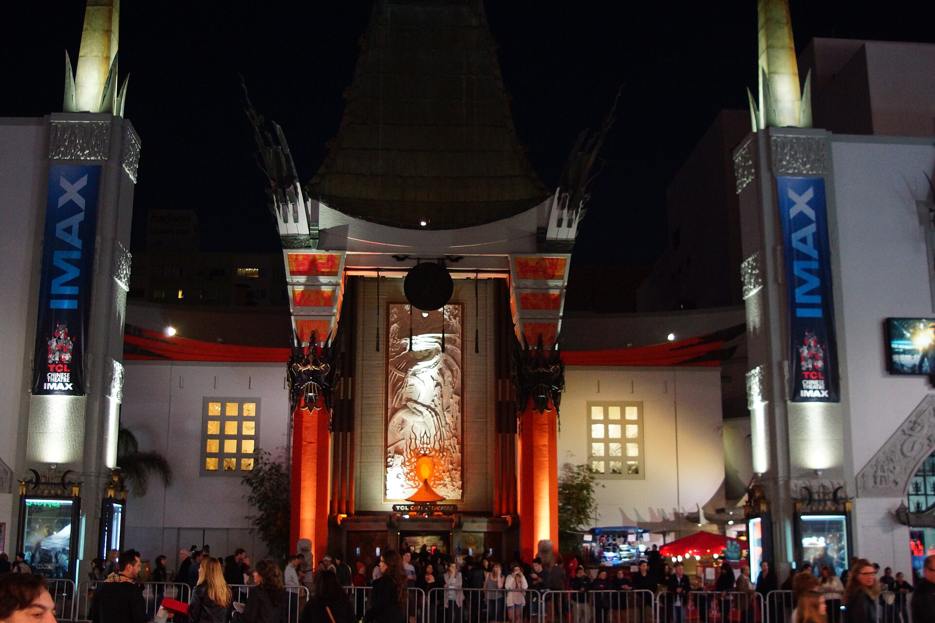 The TCL Chinese Theatre on Hollywood Boulevard at night, its facade lit red and gold with a crowd on the forecourt
