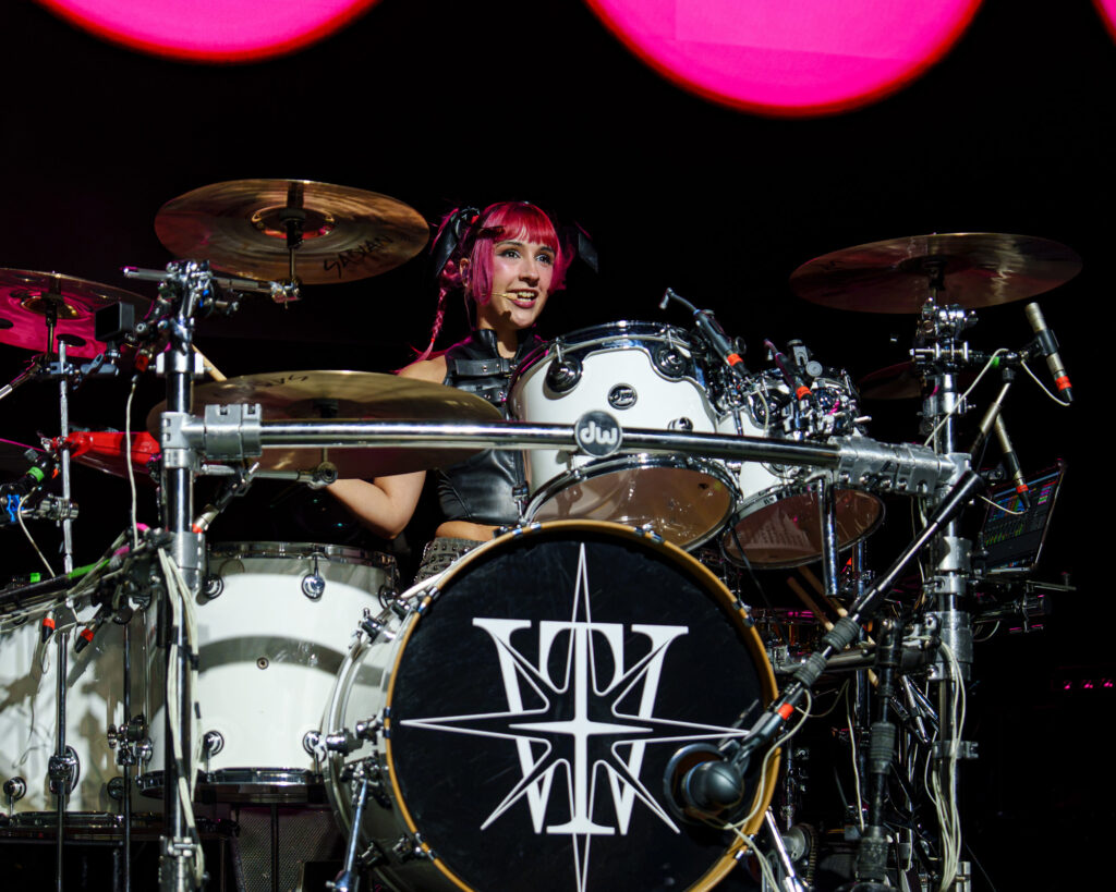 The-Warning-The-Fonda-Theater-Zharmaine-Boatman-The-824-Journal-9 – The 824 Journal The Warning at The Fonda Theatre in Los Angeles: female drummer with pink hair performing behind a white drum kit on stage with pink lights overhead.