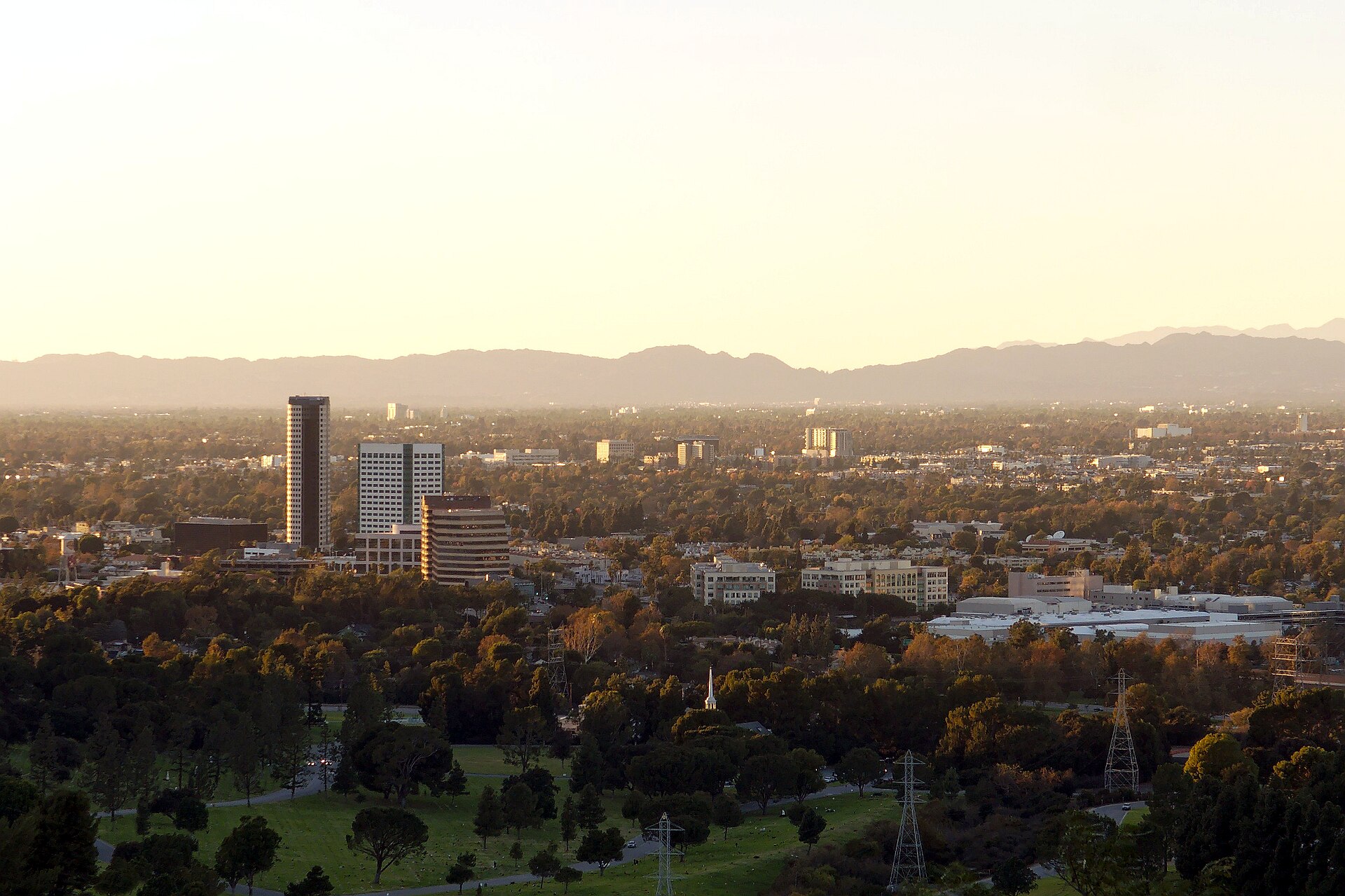 View over Burbank's media district from Griffith Park in the late afternoon, with mountains behind the city