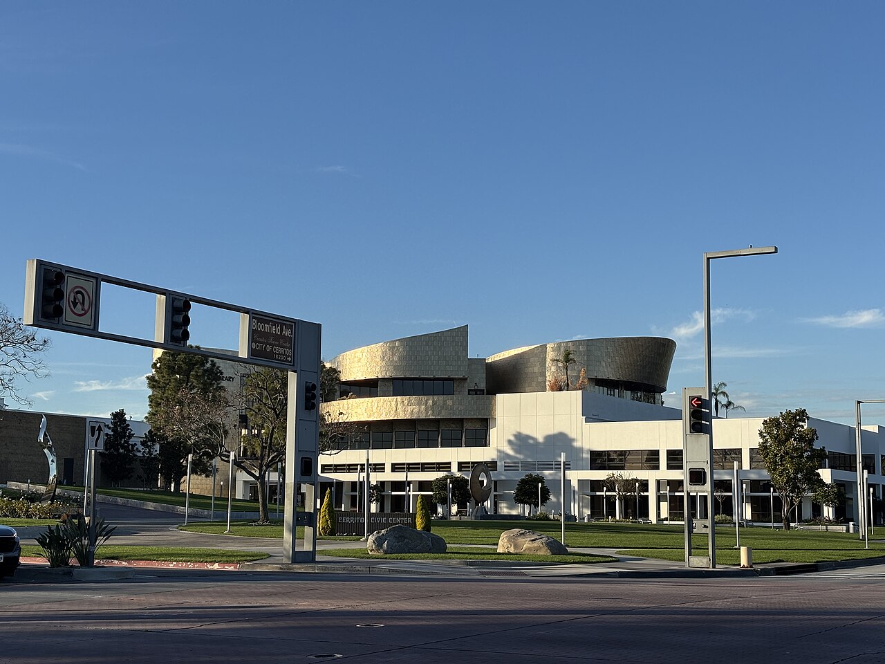 The Cerritos Civic Center building with its curved facade, seen across a street intersection under a blue sky