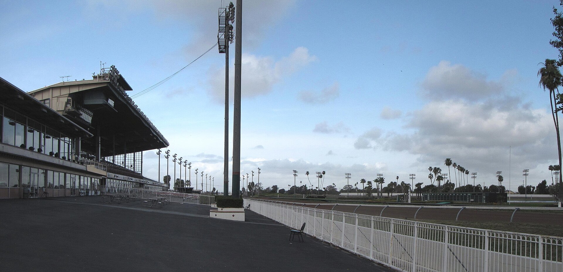 The grandstand and dirt track at Los Alamitos Race Course in Cypress under a partly cloudy sky