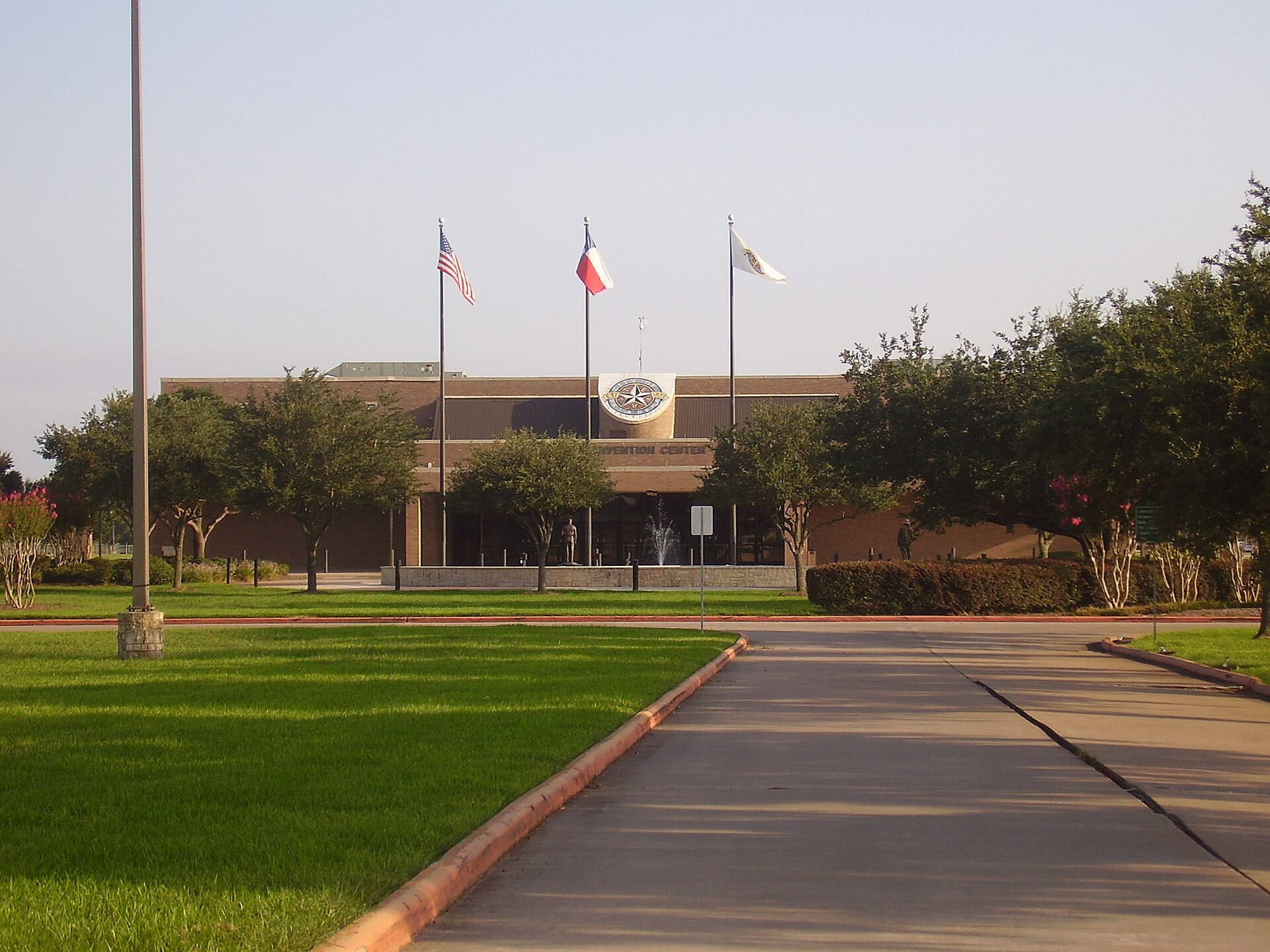 The Pasadena Convention Center exhibit hall building with flags out front and a lawn in the foreground