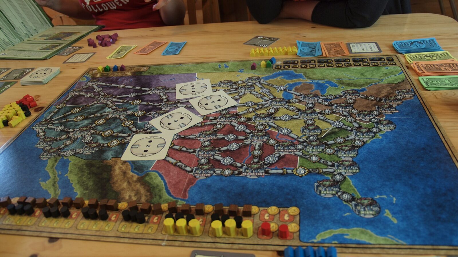 A Power Grid game board covered in colored houses, resource tokens, and power plant cards mid-game