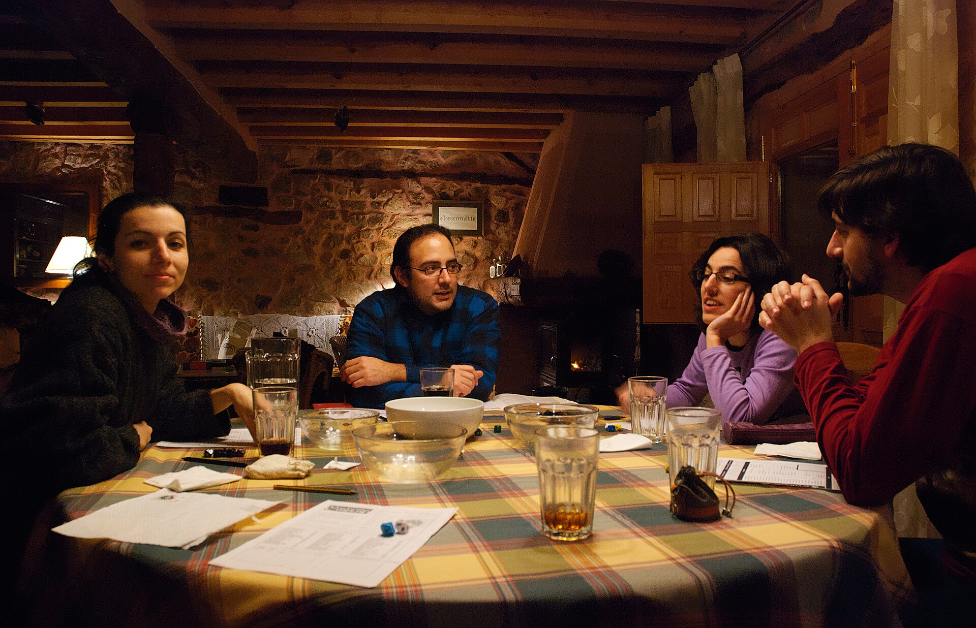 A group of role-playing gamers around a table covered in dice, character sheets, snacks, and drinks