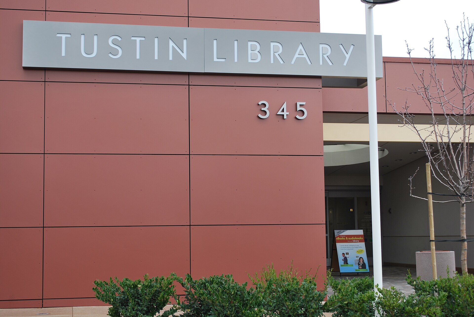 The Tustin Library sign and 345 street number on the library's red exterior wall